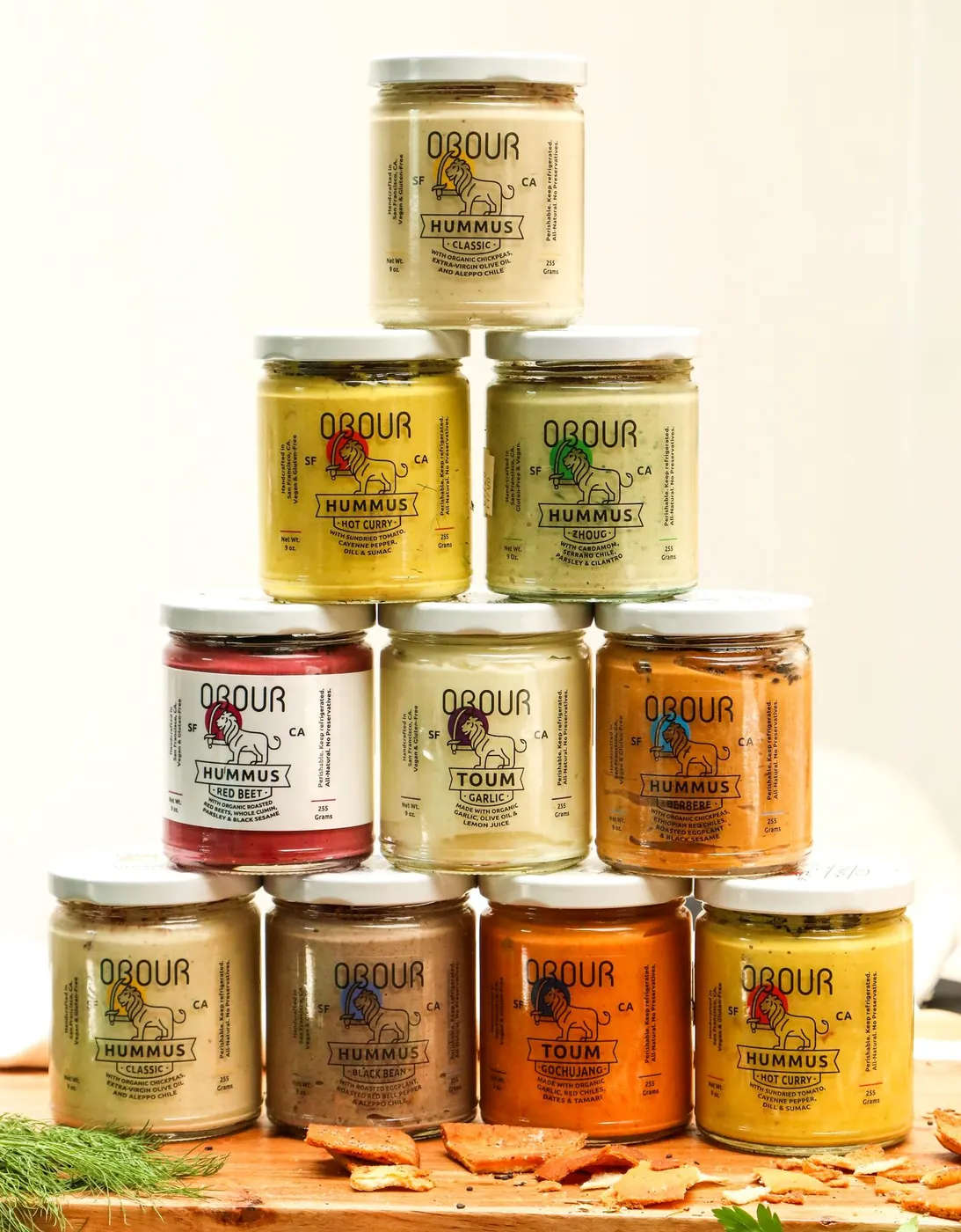 A pyramid of Obour hummus and toum jars on a cutting board