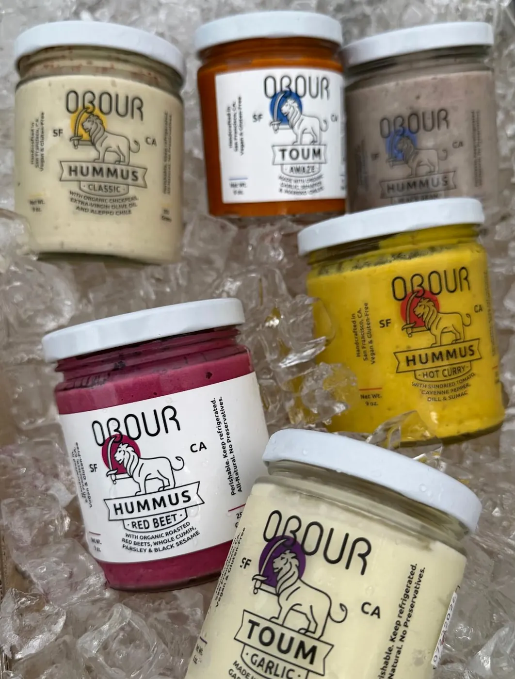 Jars of Classic, Red Beet, Hot Curry and Black Bean hummus with Garlic and Awaze toum on ice